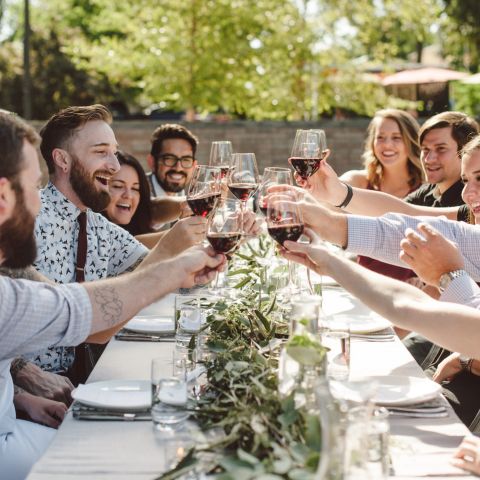 Friends toasting with wine glasses on the patio of the Hive