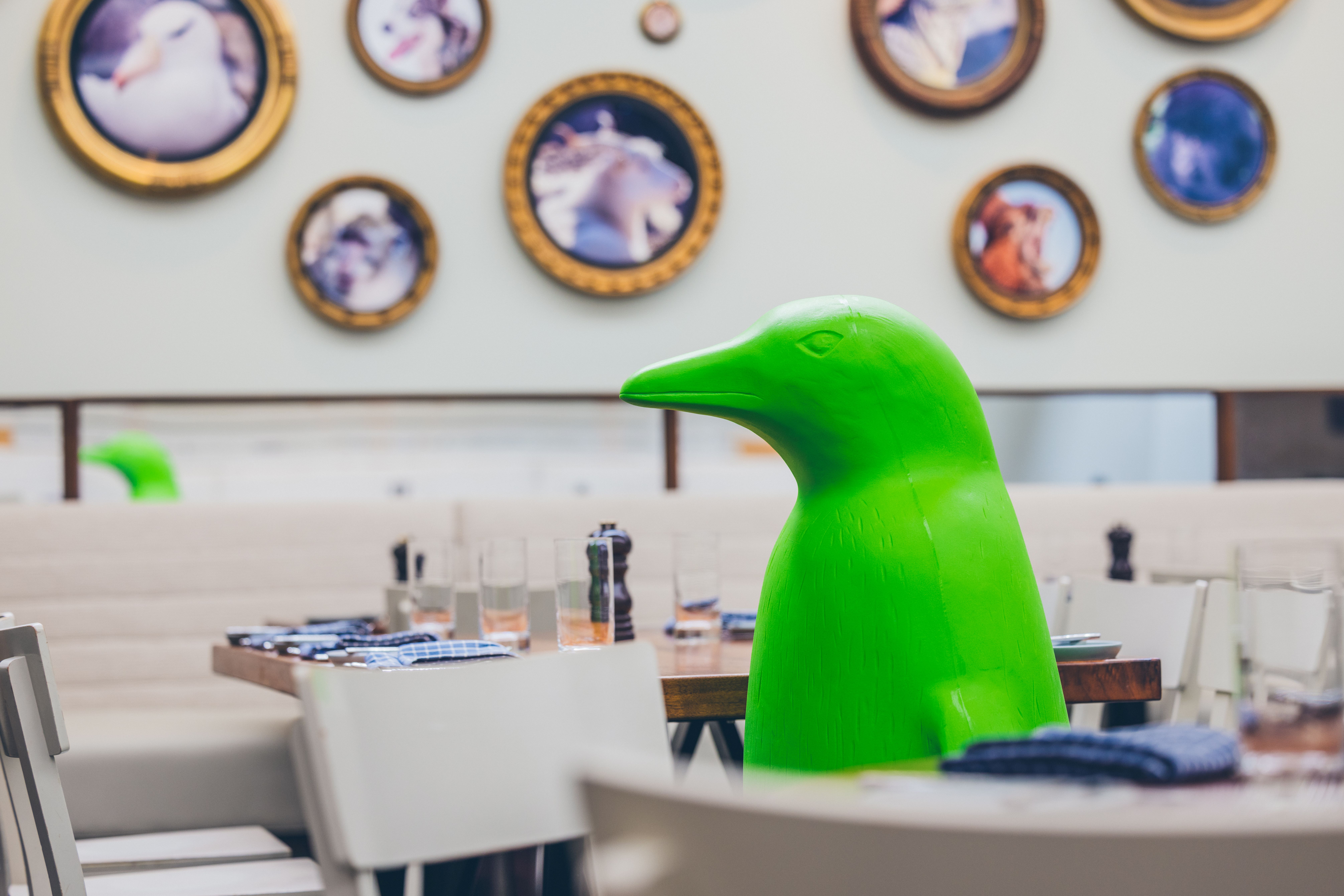 Green penguin sitting in a restaurant